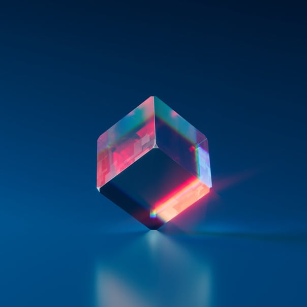 Glowing translucent cube balancing on one edge on a reflective surface against a dark blue background.